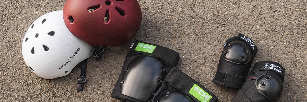 Skateboard Helme und Schutzkleidung liegen auf dem Boden