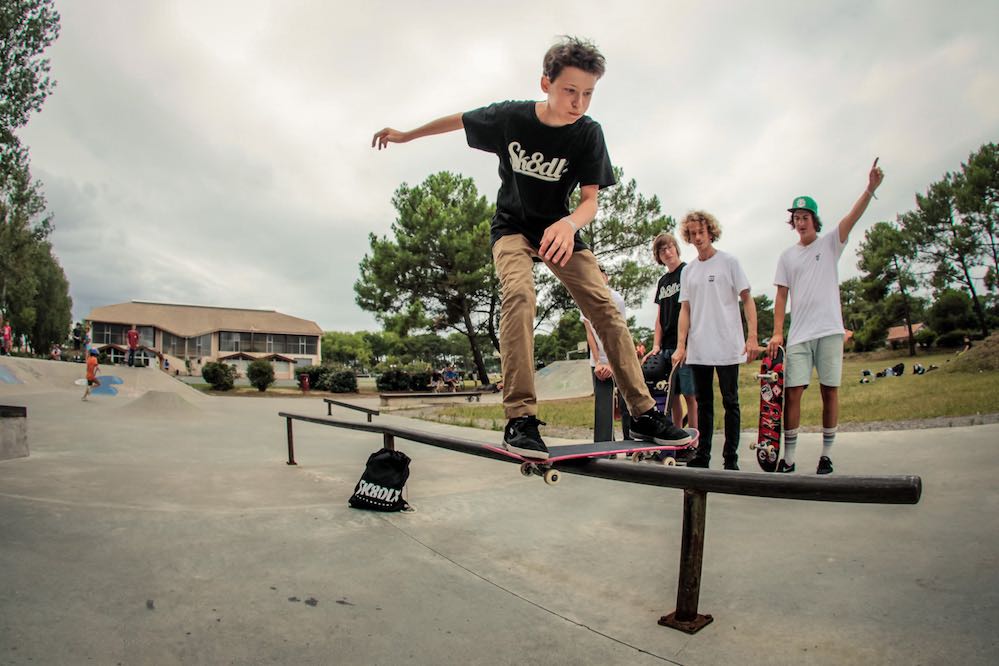 Child skates a flat rail during a skateboarding workshop