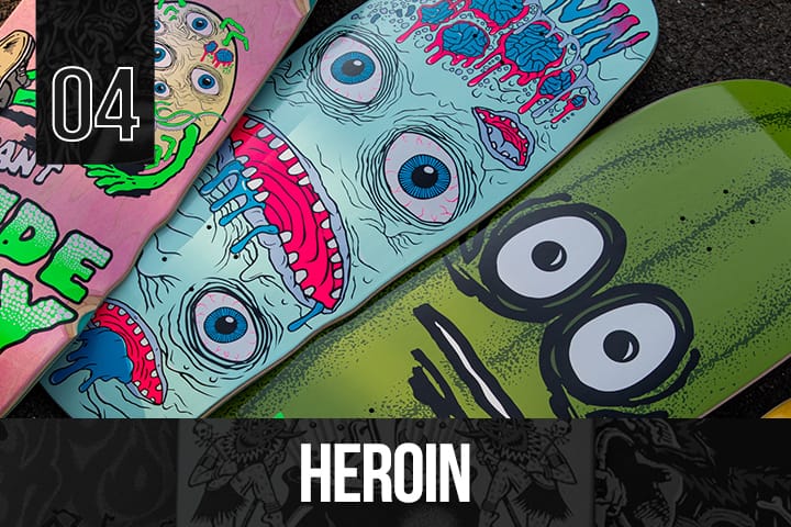 Three Heroin Skateboards decks with colorful cartoon monster faces, including blue and green designs with large eyes and expressive artwork.