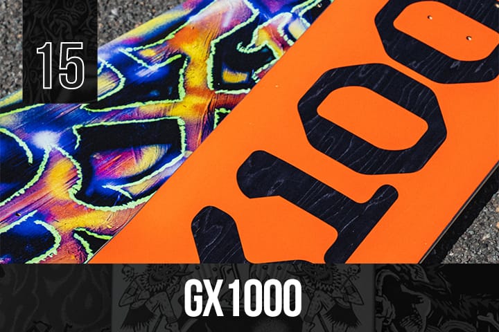 Two GX1000 skateboard decks, one with neon abstract patterns in blue and purple, the other solid orange with large black "GX1000" text, displayed on pavement.