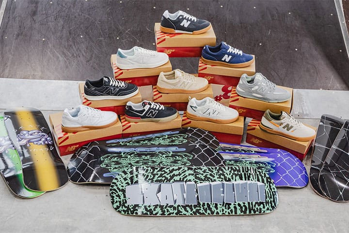 Pyramidenförmiges Display mit New-Balance-Numeric-Skate-Schuhen auf roten Kartons, davor mehrere skatedeluxe Skateboard-Decks, von denen eines mittig einen großen skatedeluxe-Schriftzug in Grün auf schwarzem Muster zeigt.