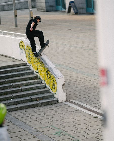 Urban skate scene in Vienna with skater doing a frontside bluntslide on a graffiti-covered ledge over a stair set.