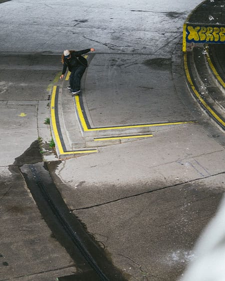 Urban skateboarding in Vienna with skater performing ride on 5050 on a ledge in black streetwear.