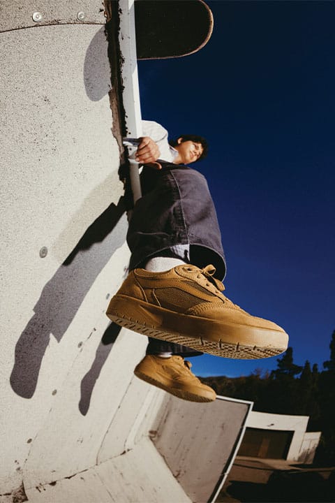 Lifestyle-Foto des Vans Z3 in Braun mit Gumsohle, gro&szlig; im Vordergrund, w&auml;hrend der Skater l&auml;ssig auf einer Kante sitzt und das Board oben in den Bildrand ragt