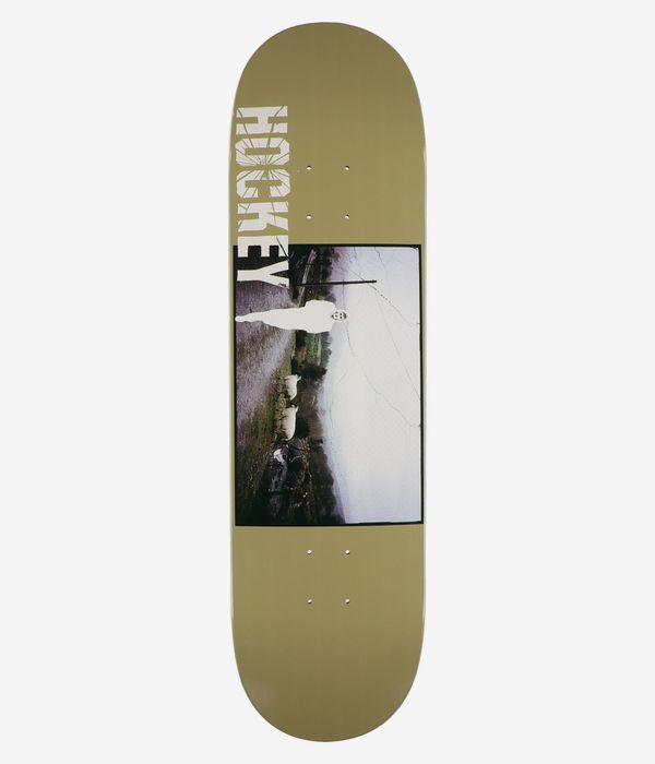Planche de skateboard HOCKEY « Stain Priest's Leap Shape #2 » de 8,44 pouces, vue de dessous — planche de couleur beige avec, au centre, un panneau photographique rectangulaire représentant une silhouette humaine blanche, des moutons en train de paître et des éléments ruraux ; grand logo HOCKEY blanc vertical à gauche. Image studio nette ; fond blanc.