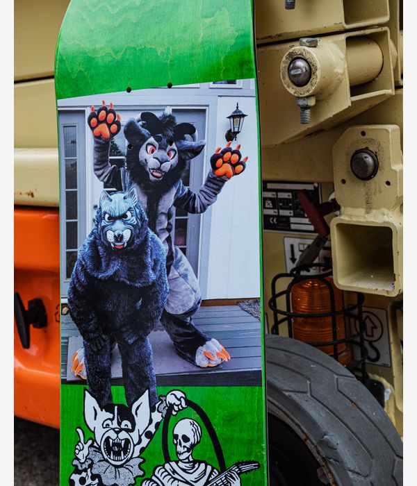 Marketing image of PALACE Benny Pro S43 8.1" skateboard deck with bright green wood-grain top and bottom bands, central photographic panel of two costumed animal figures, black-and-white cartoon skeleton graphic and small 'Palace' text, outdoor industrial background.