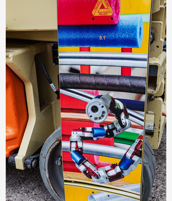 PALACE Benny Pro S43 8.1" skateboard deck — multicolor graphic with stacked bright yellow, red, blue and green bands and a futuristic robotic/mechanical illustration; Palace triangle logo and “8.1” size marking visible, lifestyle marketing image