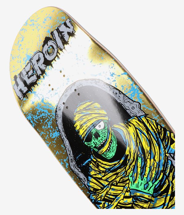 Cropped detail view of Heroin Skateboards Dead Dave KO2 Mummy 10.125" skateboard deck: white deck surface with bold cartoon green skull wrapped in yellow bandages, black hood and distressed "HEROIN" text, gold and turquoise paint splatter. Clean Studio image; white background