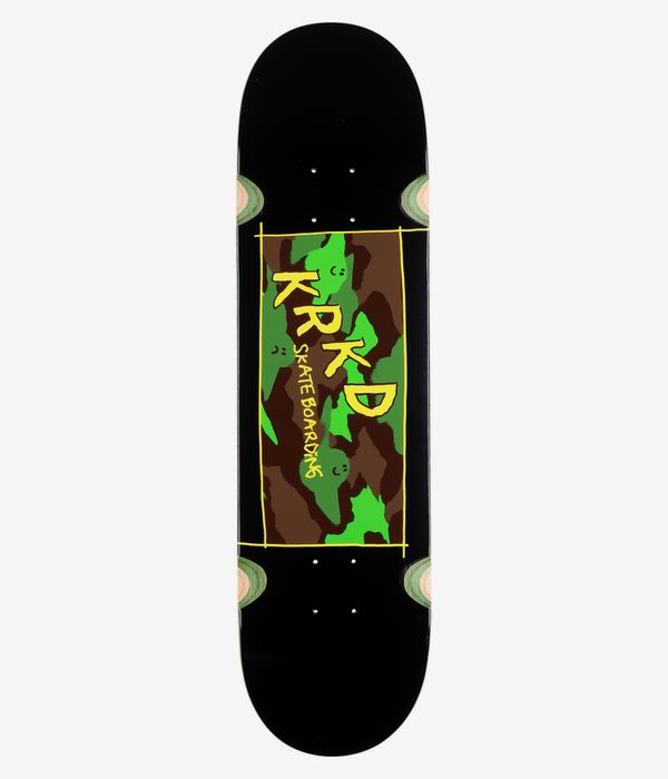 Vue de dessous complète de la planche de skateboard « Krooked Kamo Wheel Wells » 8,25 pouces : planche noire unie avec, au centre, un motif camouflage rectangulaire de style bande dessinée (vert, marron) et de grands lettrages jaunes « Krooked » et « Skate Boarding ». Image studio nette ; fond blanc.