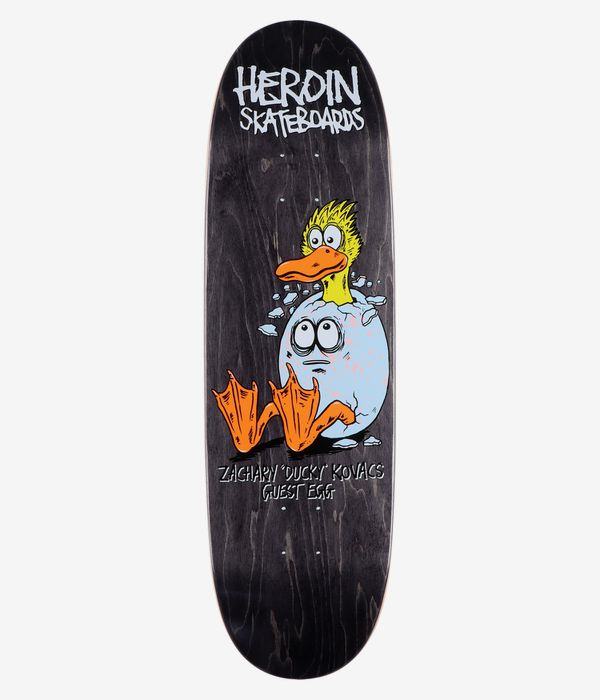 Heroin Skateboards Zacahry Ducky Kovacs Guest Egg 9,125" skateboarddeck, volledig onderaanzicht: achtergrond van zwart gebeitst hout met in het midden een gele cartoon-eend die uit een gebarsten lichtblauw ei tevoorschijn komt, met een oranje snavel en poten, witte accenten en het zichtbare „Heroin Skateboards”-logo en de naamtekst; strakke studiofoto, witte achtergrond.
