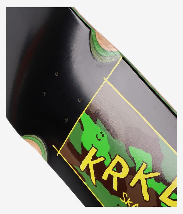 Nahaufnahme eines „Krooked Kamo Wheel Wells 9"“-Skateboard-Decks in glänzendem Schwarz mit einer rechteckigen Cartoon-Grafik: grüne Kreaturensilhouette und große gelbe „KRK“-Buchstaben über braun-grünen Formen. Klares Studiobild; weißer Hintergrund.